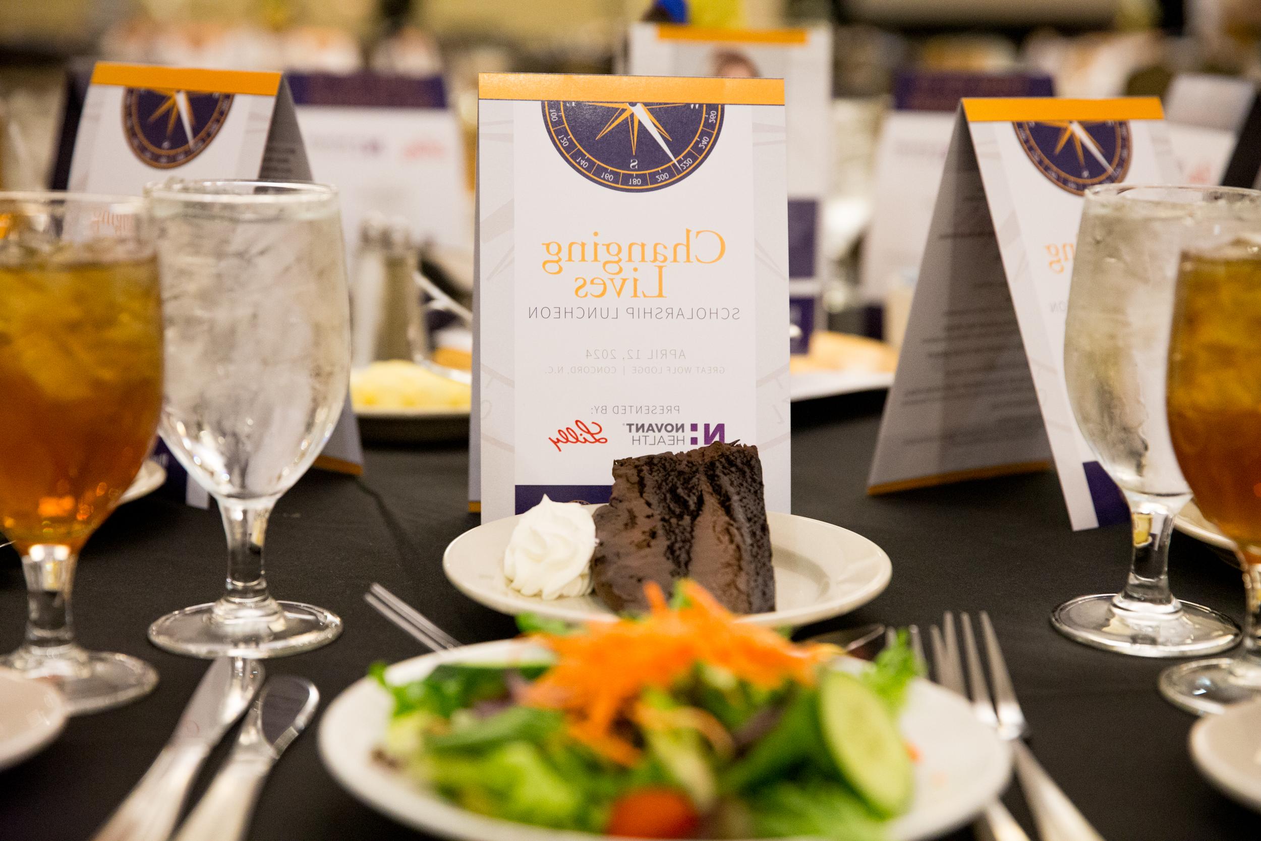 Formal luncheon table setting with dessert, salad, drinks, and an event information card.